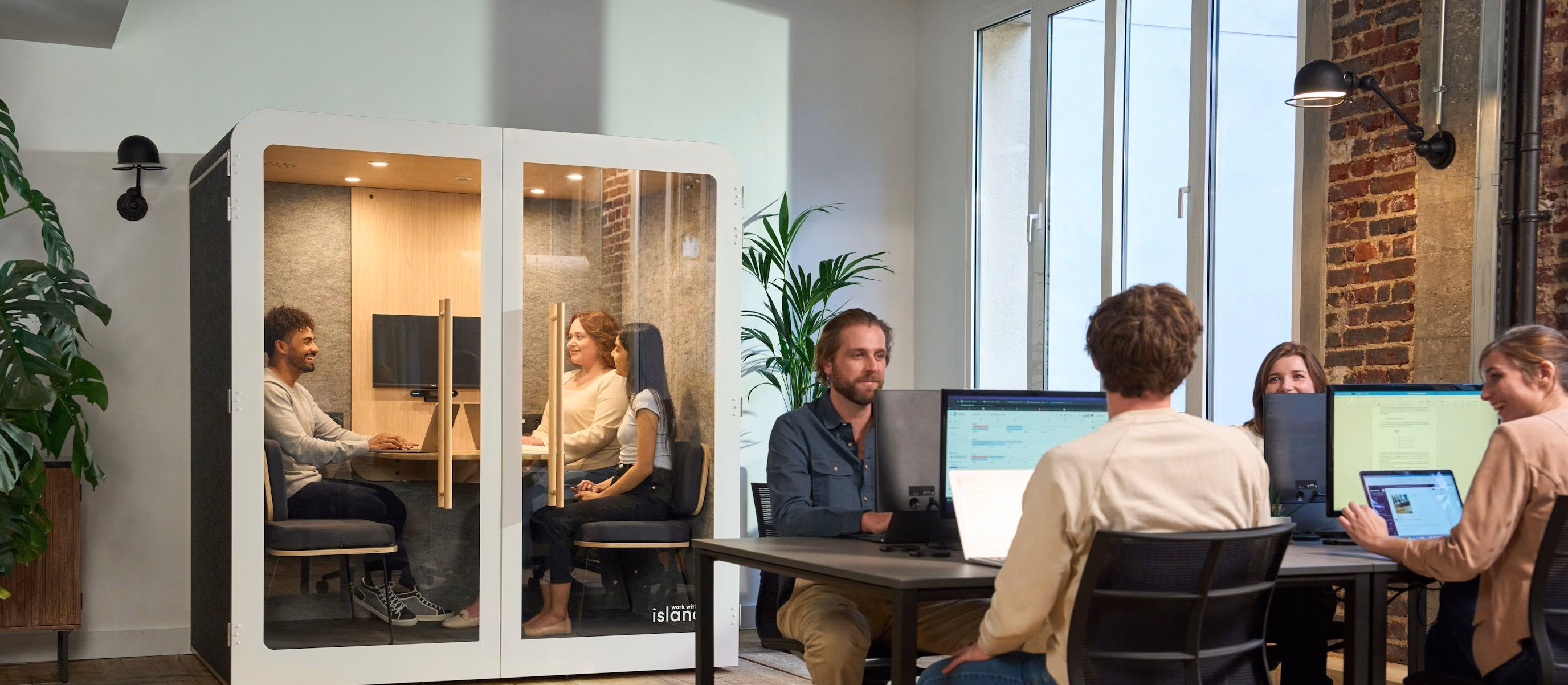 A team working together at a long table full of laptops in a bright office.