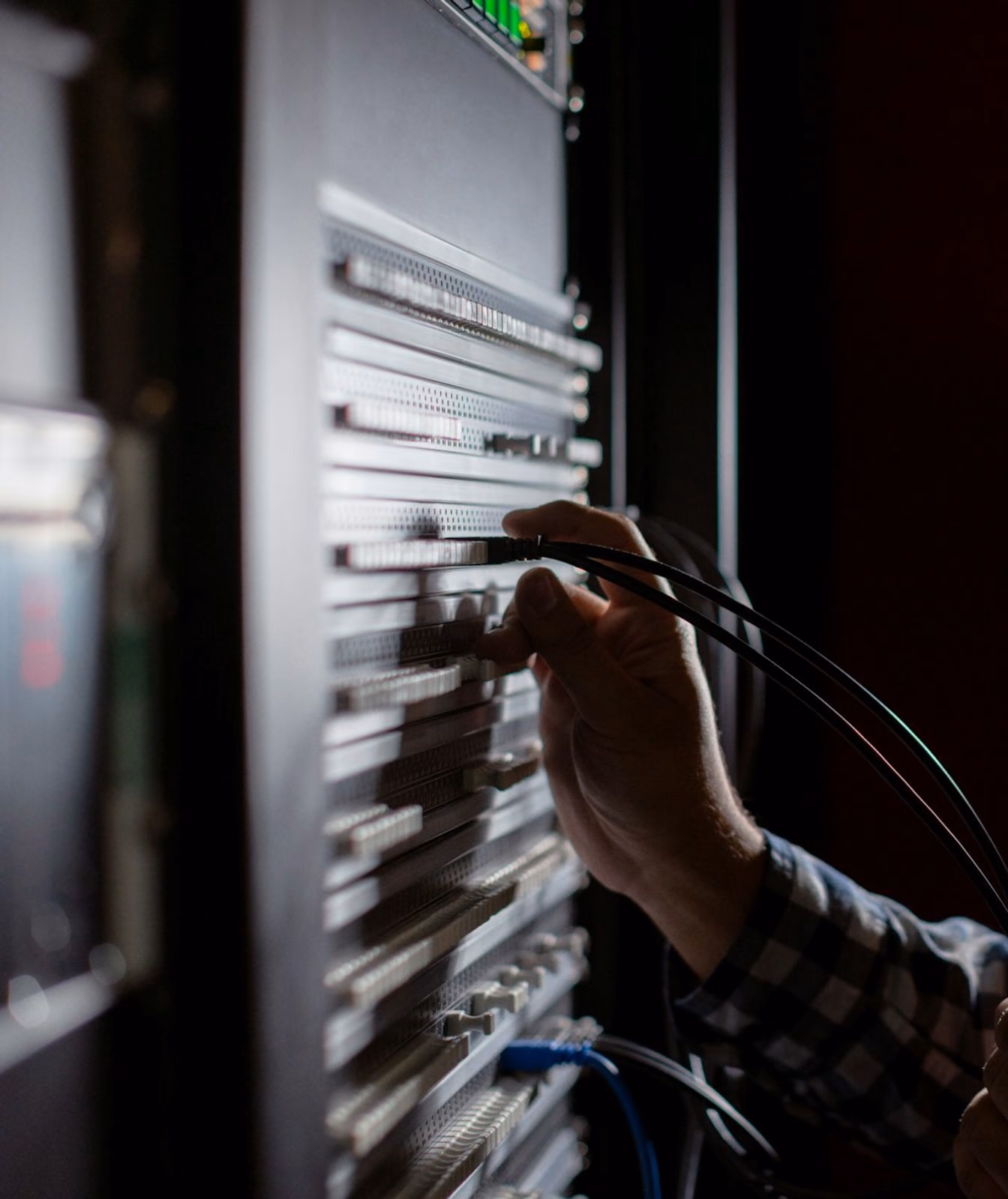 An engineer working on equipment inside a server rack.