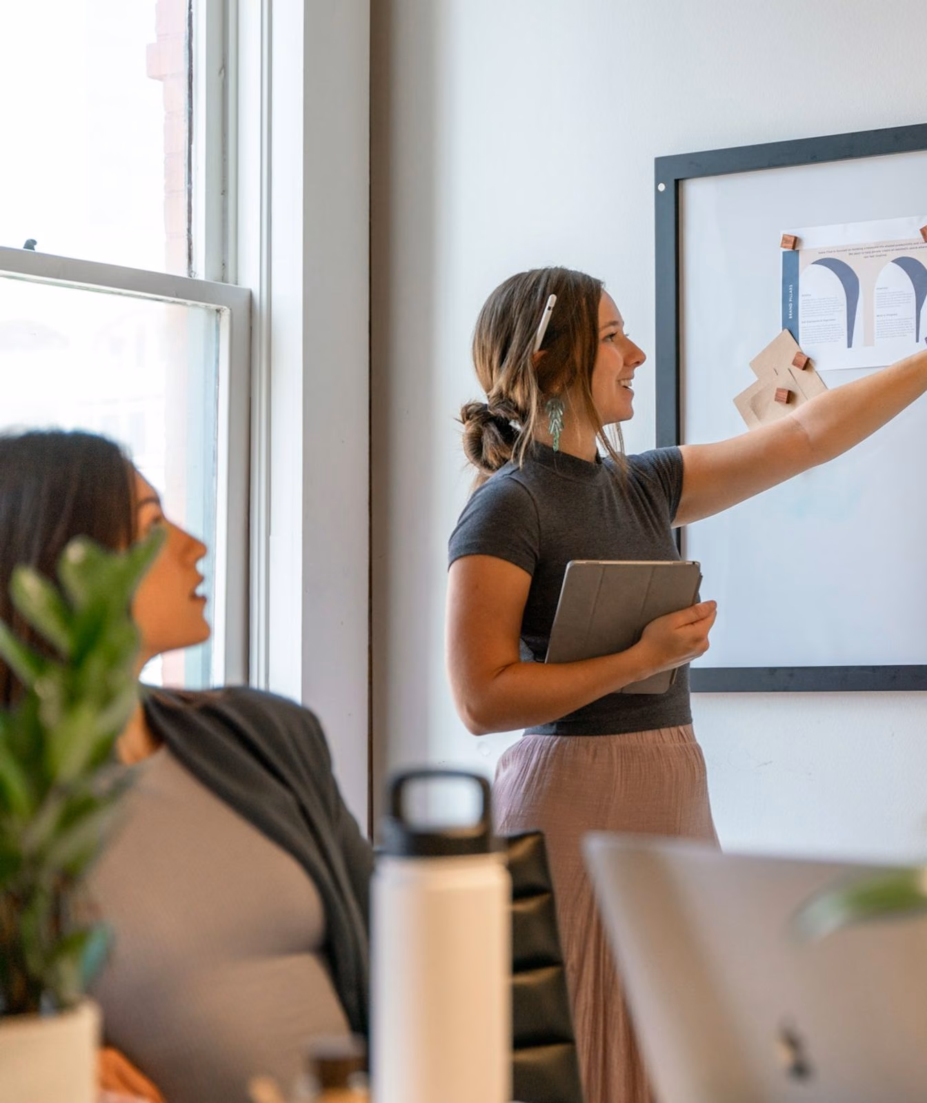 A consultant walking colleagues through charts pinned to a wall.