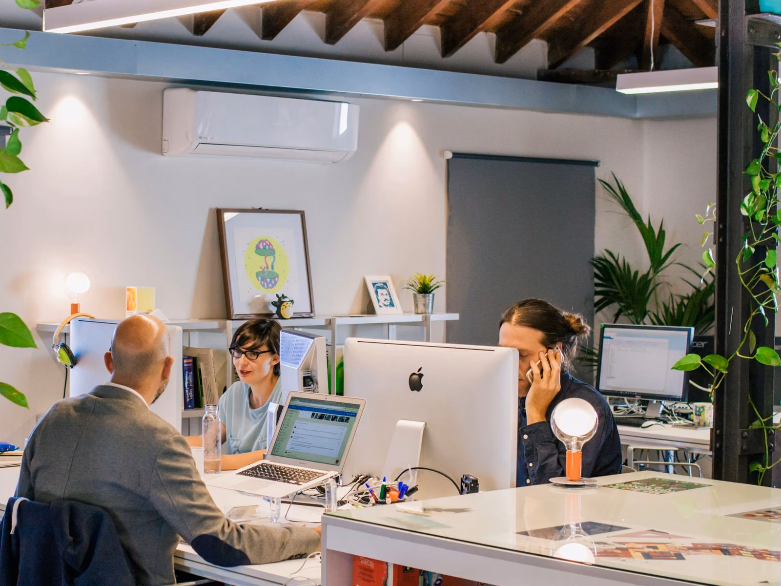 Colleagues at their desks comparing notes across a shared workspace.